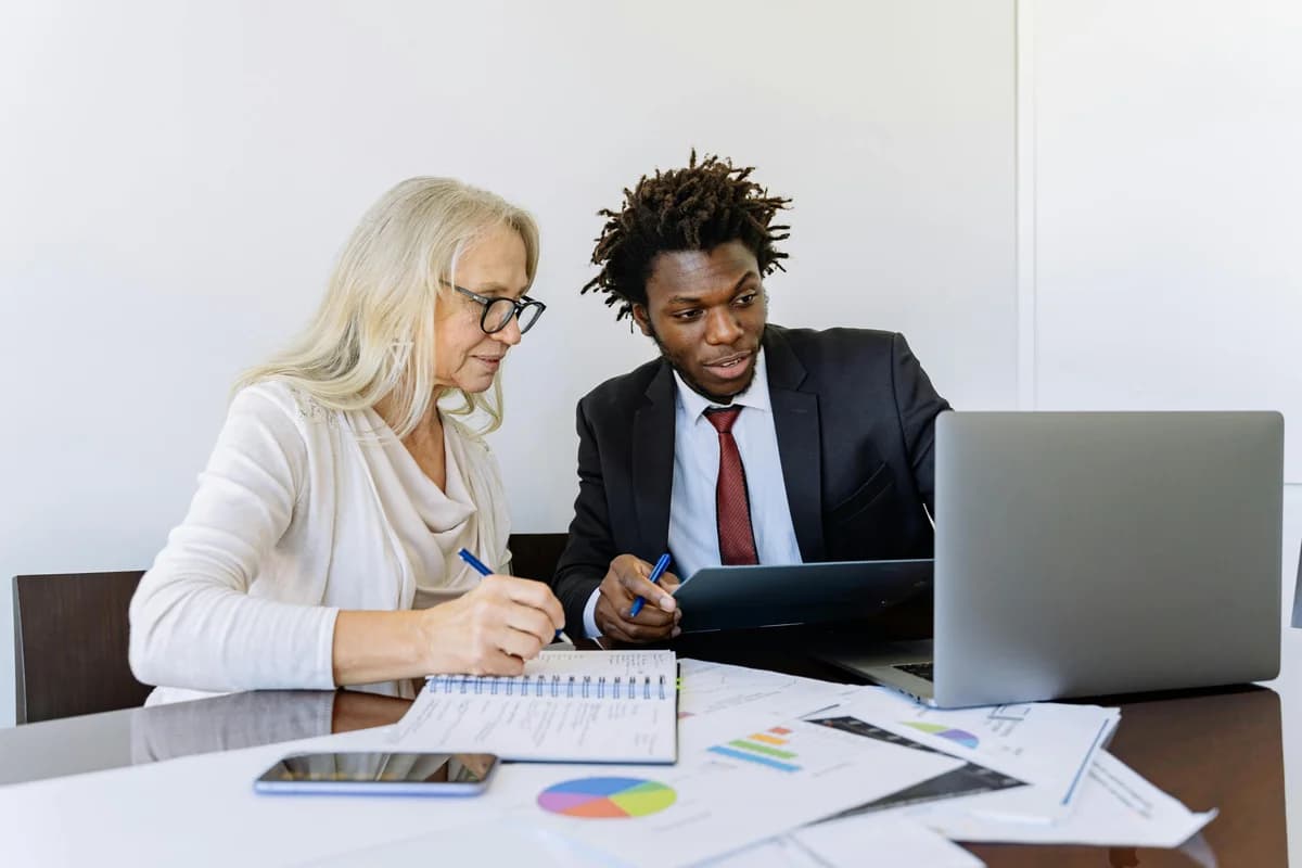 Two colleagues reviewing work together at a laptop